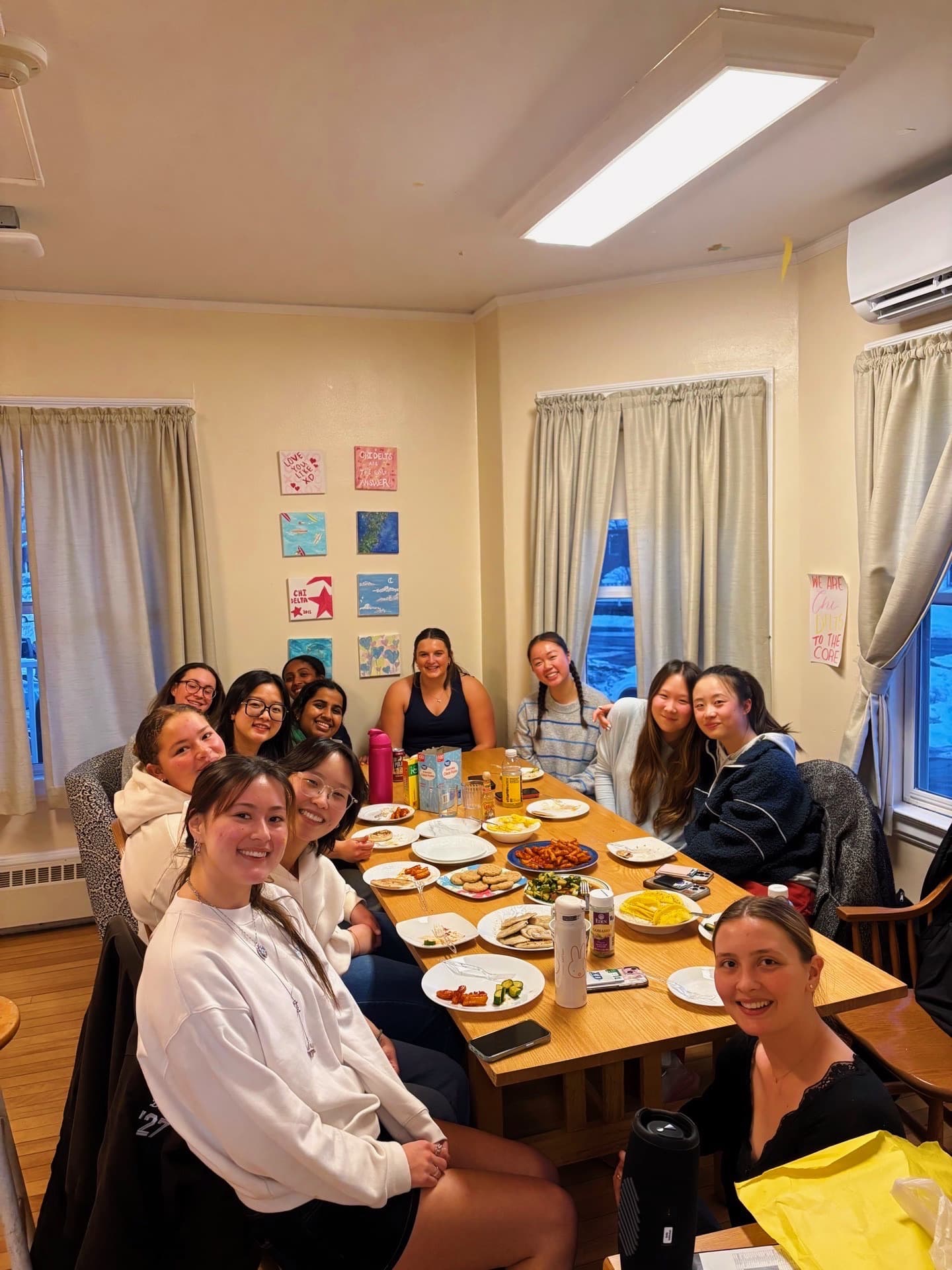 Sisters around the long table in the haus dining room, plates of home-cooked dishes between them