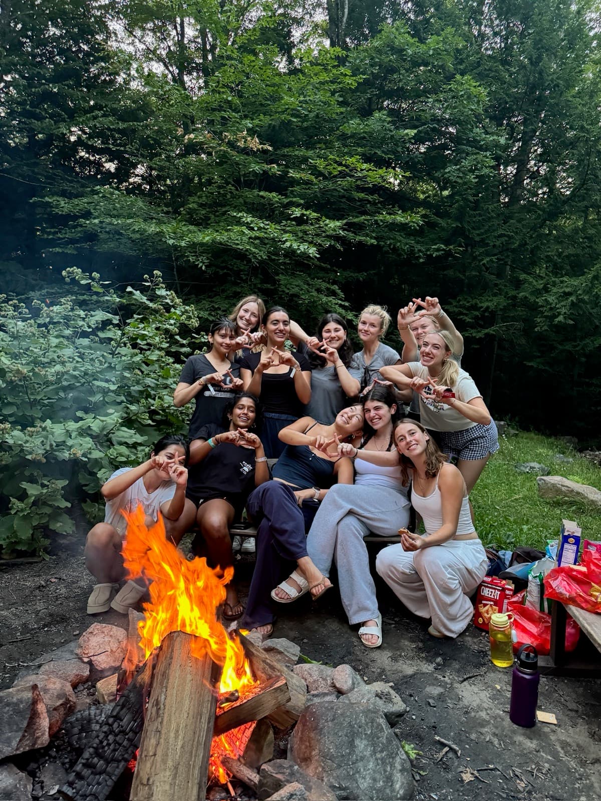 Sisters making XD hand signs around a campfire