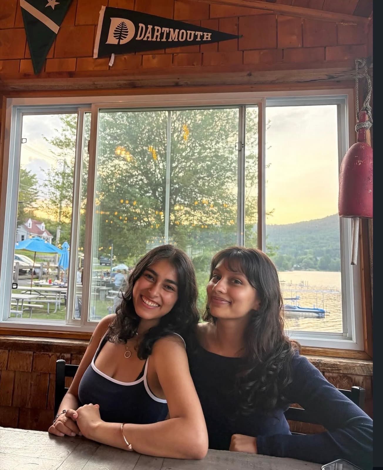 Two sisters at dinner by the lake, Dartmouth pennant on the wall