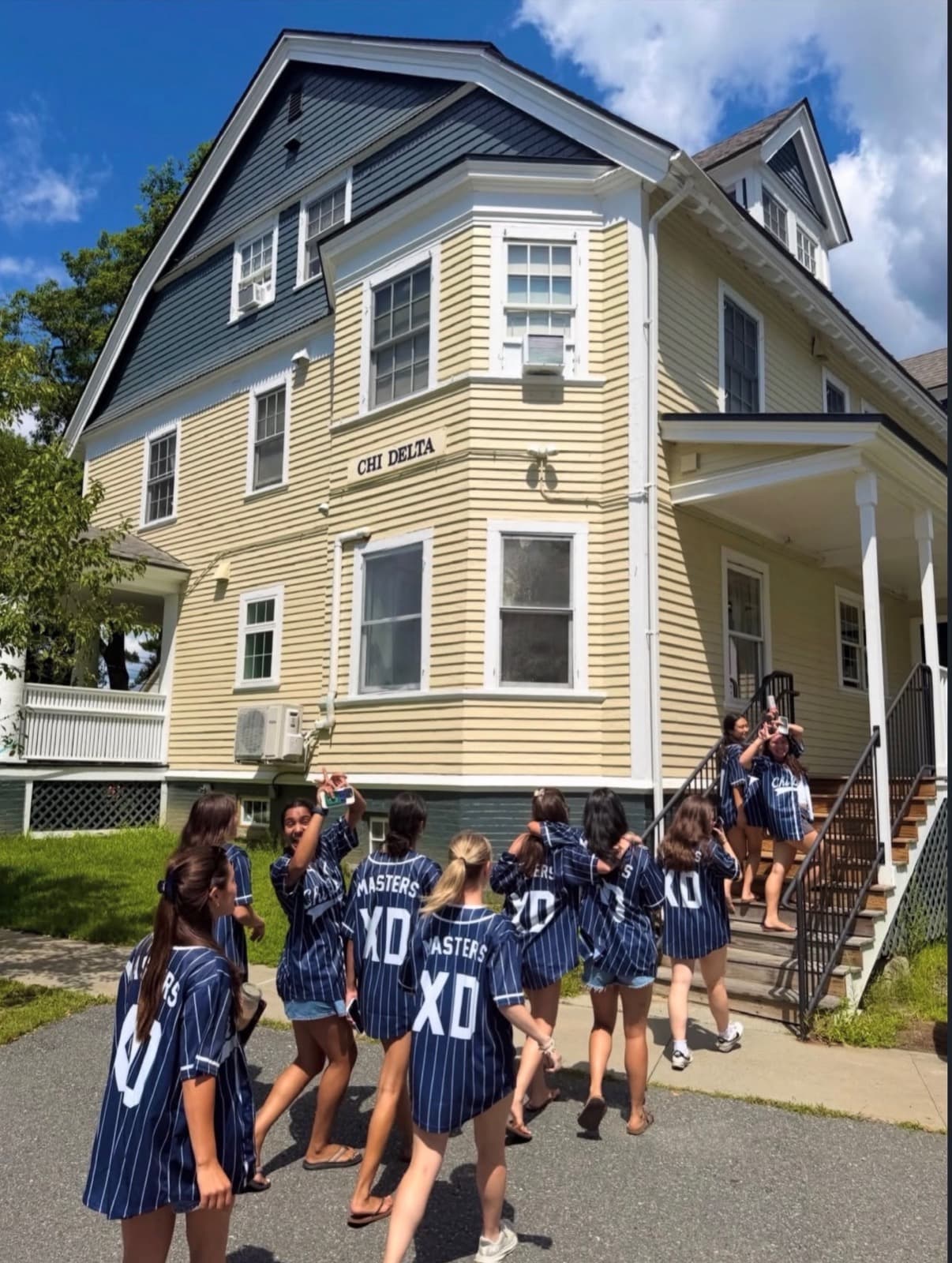 Sisters in pinstripe jerseys walking up to the Chi Delta house