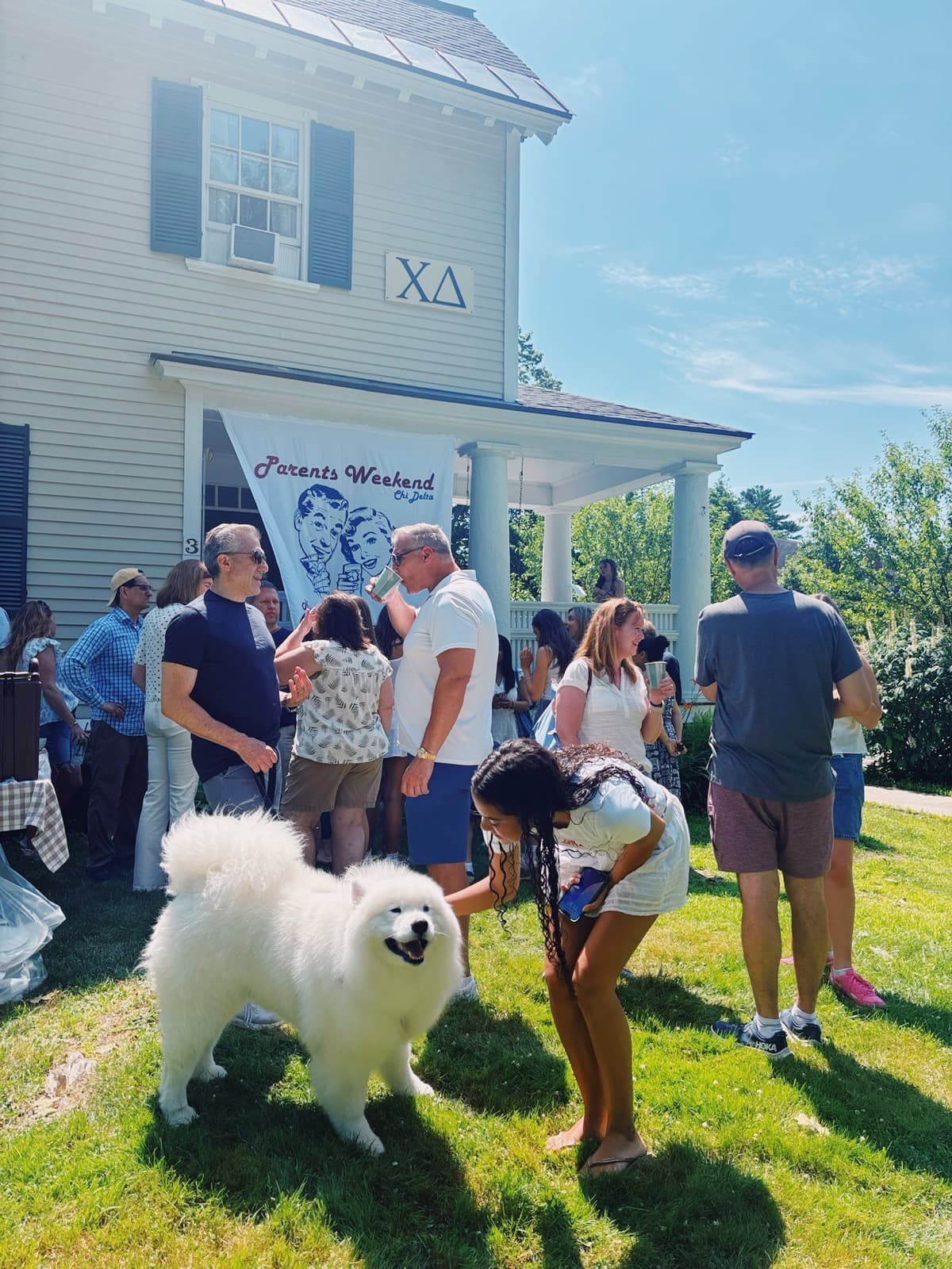 Parents Weekend at the Chi Delta house, with a sister petting a dog