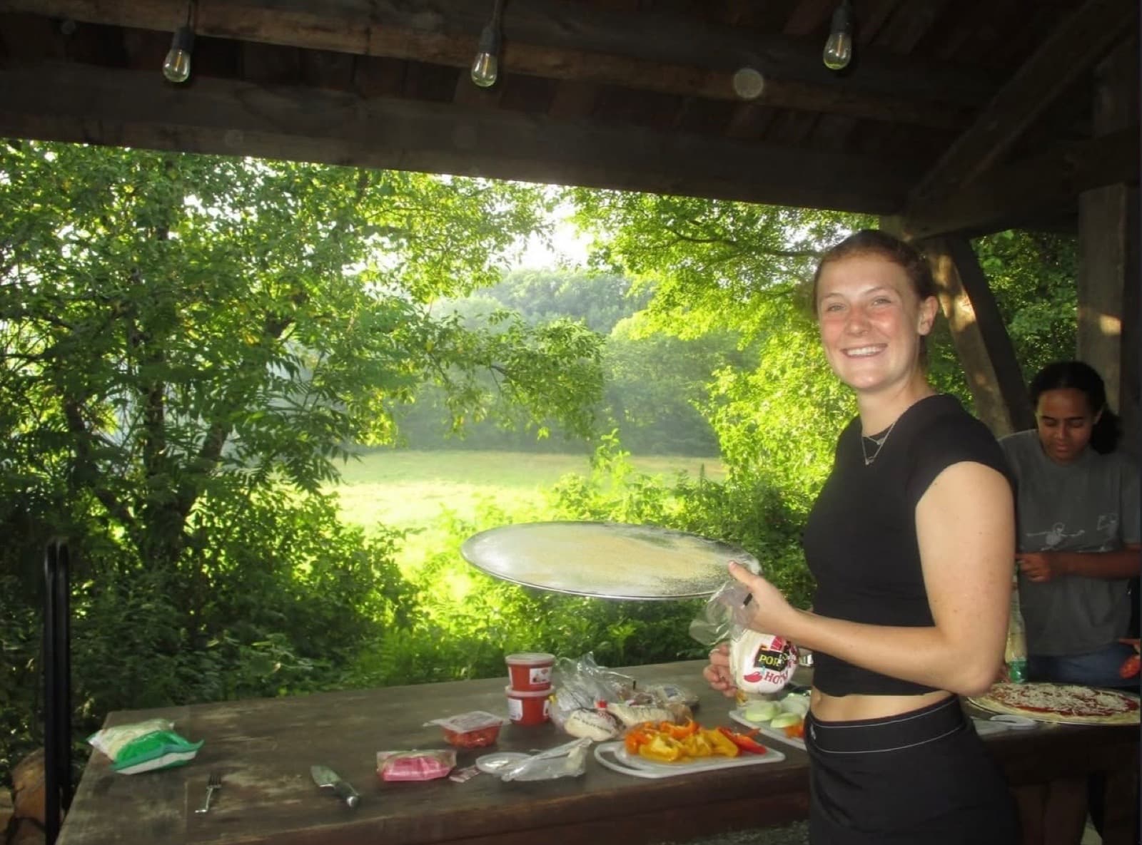 A sister prepping pizza toppings at an outdoor table