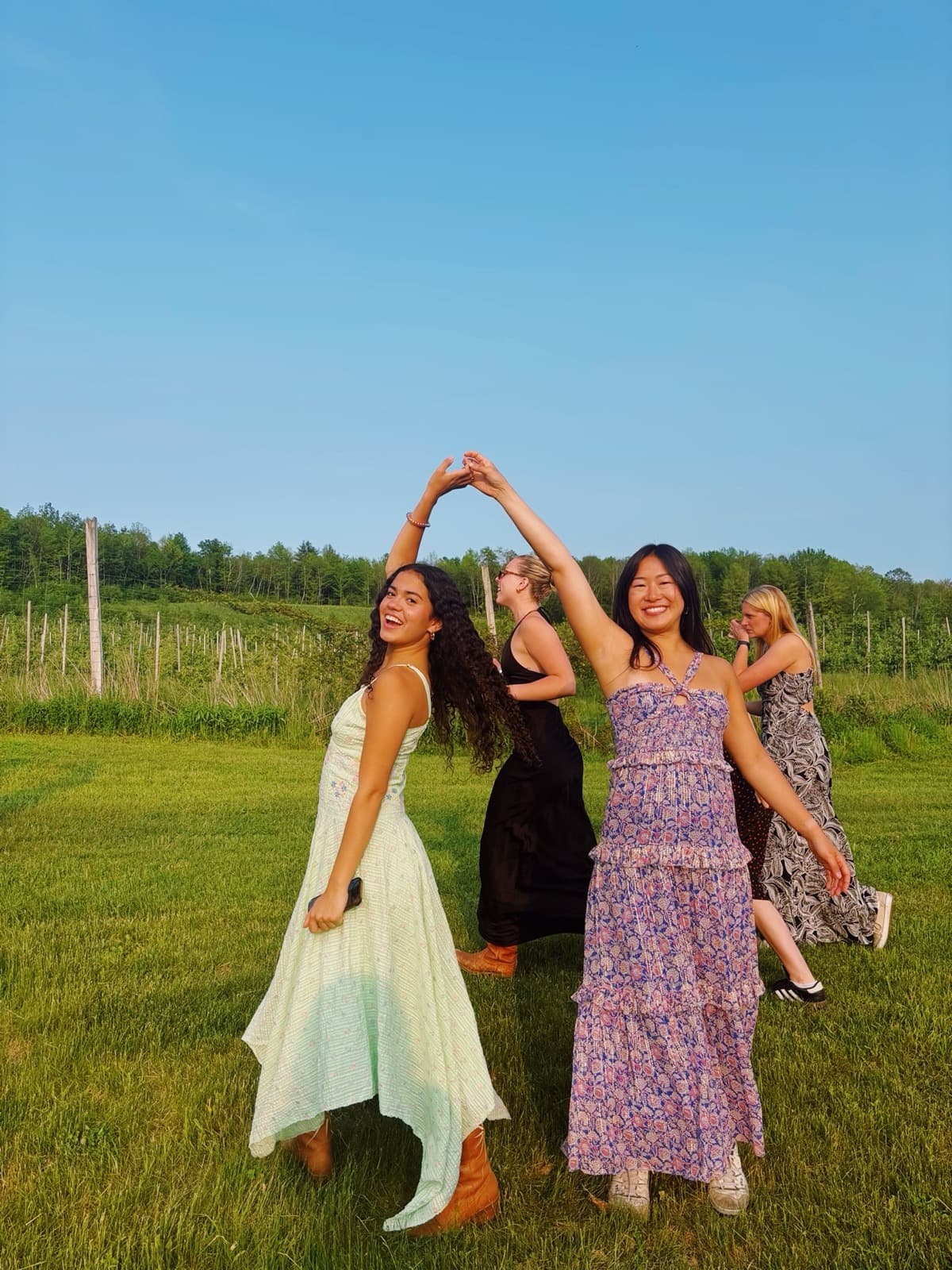 Sisters in dresses making an XD hand sign in a vineyard